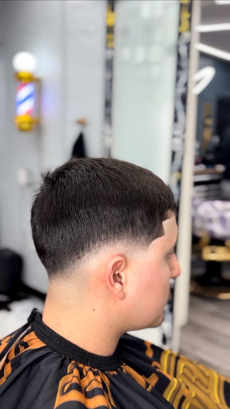 Low taper fade with textured crop — BB cape and barber pole