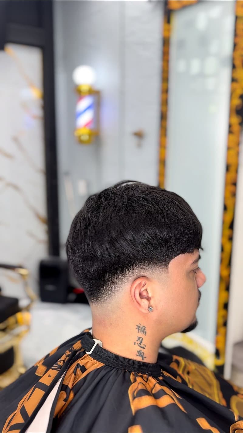 Low taper fade back view — tattoo detail and barber pole