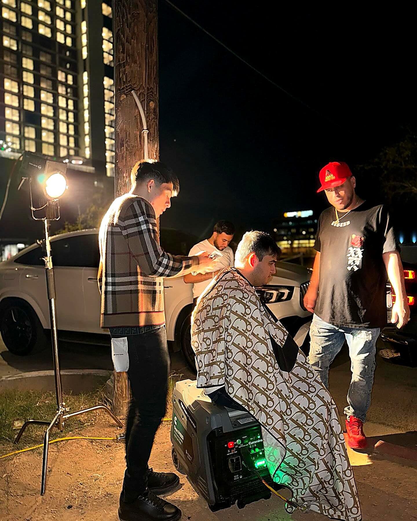 Joel cutting hair outdoors at night — Billionaire Barbershop